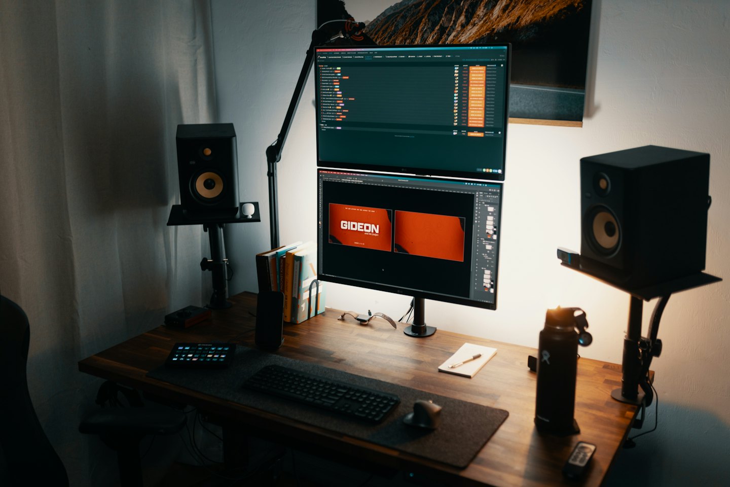 Dual monitors with design software sit on a wooden desk.